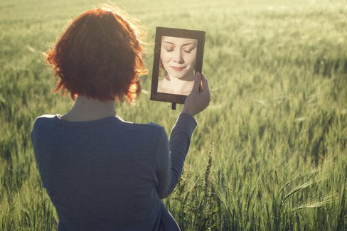 دختری میان سبزه ها در آینه به خود ناراحتش نگاه می کند